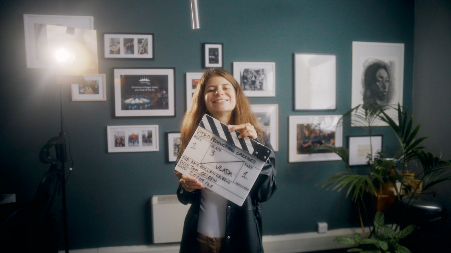 Nomadic UK staff member holding a clapper board on a shoot in their office