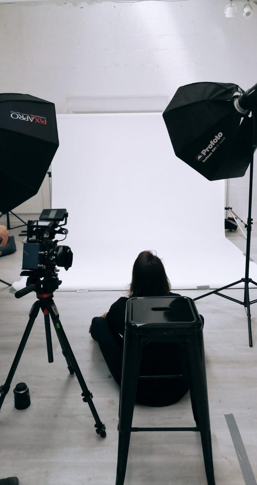 Nomadic UK – Empty studio with two lights and a video camera Nomadic UK - Empty white studio with two lights and a photographer and a cinema camera